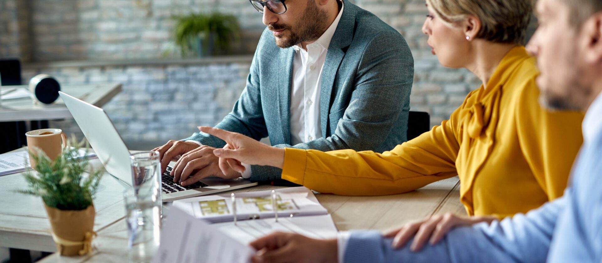 Real estate agent using laptop while having a meeting with a couple in the office.