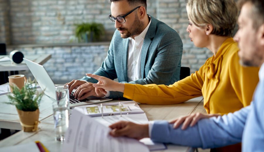 Real estate agent using laptop while having a meeting with a couple in the office.