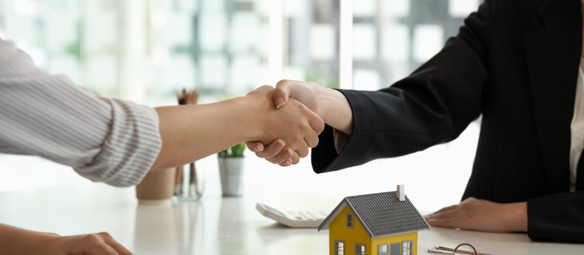 Real estate broker and customer shaking hands after signing a contract: real estate, home loan and insurance concept