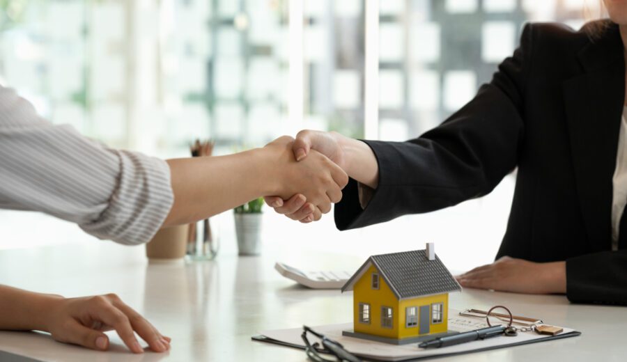 Real estate broker and customer shaking hands after signing a contract: real estate, home loan and insurance concept